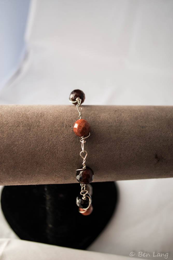 Each goldstone bead in this bracelet is wrapped in wire, and the wire loops link the beads together