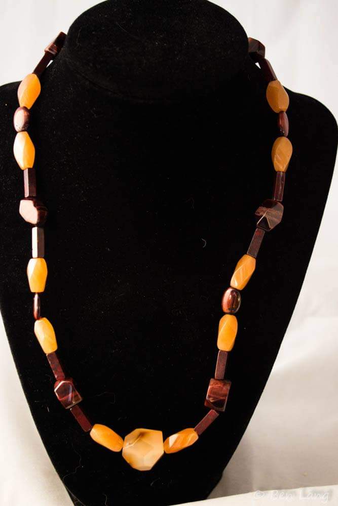 This necklace is in shades of brown and red, with a faceted piece of Tiger Eye in the middle